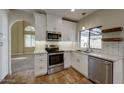Modern kitchen with stainless steel appliances, white cabinetry, and views of the adjacent living area at 1010 N Osprey Ct, Gilbert, AZ 85234