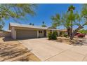 Single story home with a spacious driveway and desert landscaping under a clear blue sky at 1115 E Carter Dr, Tempe, AZ 85282