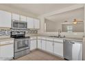Well-lit kitchen showcasing stainless steel appliances, white cabinets, and an open layout at 15802 W Watson Ln, Surprise, AZ 85379