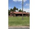 Charming single-story brick home with a well-manicured front lawn, mature landscaping and a classic red tile roof at 20 W Pasadena Ave, Phoenix, AZ 85013