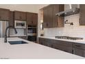 Up close view of modern kitchen with stainless appliances, a white island with sink, and gray backsplash at 3824 W Lodge Dr, Laveen, AZ 85339