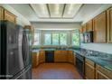 Well-lit kitchen boasts granite counters, wood cabinets, black appliances, and a bay window at 1226 E Greenway Cir, Mesa, AZ 85203