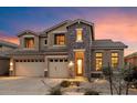 Gorgeous two-story home with a stone accent exterior and a spacious three-car garage at dusk at 35206 N 27Th Ave, Phoenix, AZ 85086