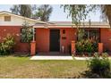 Close-up of a red brick home highlighting the front door, decorative columns, and vibrant flower beds at 3741 W Davidson Ln, Phoenix, AZ 85051