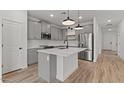 Modern kitchen with grey cabinetry, stainless steel appliances, a center island, and wood-look tile flooring at 42405 W Peters Dr, Maricopa, AZ 85138