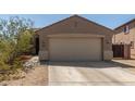 Tan single-Gathering home featuring a two-car garage and low maintenance desert landscaping in the front at 829 S 111Th Dr, Avondale, AZ 85323