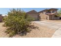 A tan single Gathering home with a two car garage sits behind desert landscaping at 829 S 111Th Dr, Avondale, AZ 85323
