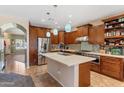 Well-equipped kitchen with stainless steel appliances, a center island, pendant lighting, and brown cabinetry at 13313 W Indianola Ave, Litchfield Park, AZ 85340