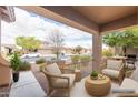 Cozy covered patio with comfortable woven seating and views of the landscaped front yard at 1453 W Birch Rd, San Tan Valley, AZ 85140