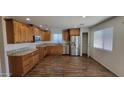 Modern kitchen featuring wood cabinets, granite countertops, and stainless steel appliances, complemented by wood flooring at 23929 W Twilight Trl, Buckeye, AZ 85326