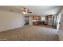 Spacious living room with carpet flooring, ceiling fan, and a view of the modern kitchen at 23929 W Twilight Trl, Buckeye, AZ 85326