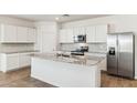 Bright kitchen with white cabinets, stainless steel appliances, and a granite island at 25467 W Graham Trl, Buckeye, AZ 85326