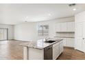 Open-concept kitchen with a large island, wood flooring, and bright lighting at 25467 W Graham Trl, Buckeye, AZ 85326
