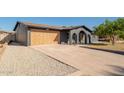 Wide shot showing the home's garage, driveway, and modern, painted brick exterior with beautiful desert landscaping at 3824 W Carol Ave, Phoenix, AZ 85051