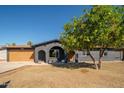 Charming single-story home featuring a welcoming arched entryway and a mature shade tree in the front yard at 3824 W Carol Ave, Phoenix, AZ 85051