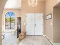 Bright foyer with grand chandelier, white double doors, and view to living area with a beautiful arched window at 3951 E Sequoia Trl, Phoenix, AZ 85044