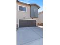 Exterior view showcasing the two-car garage with a gray door and concrete driveway at 7437 S 75Th Dr, Laveen, AZ 85339