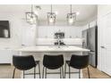 A modern kitchen features white cabinets, stainless steel appliances, pendant lights, and an island with seating at 8343 E Irwin Ave, Mesa, AZ 85209