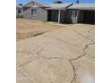 Cracked concrete driveway leading to the carport and front of the gray exterior house at 1630 E Catalina Dr, Phoenix, AZ 85016