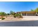 Exterior of house with a well-manicured desert landscape and a spacious three-car garage at 16562 N 109Th Way, Scottsdale, AZ 85255