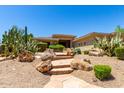 A Desert home featuring a stone walkway lined with lush landscaping and desert plants at 16562 N 109Th Way, Scottsdale, AZ 85255