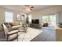 Bright living room featuring neutral tones, a ceiling fan, and a sliding glass door to the patio at 29870 W Weldon Ave, Buckeye, AZ 85396