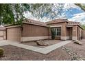 Tan home featuring a two car garage and desert landscaping, with a sidewalk leading to the front door at 3212 W Lucia Dr, Phoenix, AZ 85083