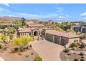 Aerial view of a desert community home with a tile roof, lush landscaping, and multi-car garage at 3217 N Piedra Cir, Mesa, AZ 85207