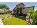 Charming stone home with a well-manicured lawn, flower beds, and a brick walkway leading to the front door at 5226 S Fairchild Ln, Chandler, AZ 85249