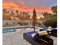 Inviting backyard pool with lounge chairs, umbrella, and a beautiful sunset view at 5226 S Fairchild Ln, Chandler, AZ 85249