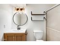 Updated bathroom with modern vanity, round mirror, open shelving, and glass shower at 5809 E Thomas Rd, Scottsdale, AZ 85251