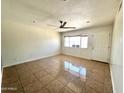 Bright, empty living room with ceramic tile, a ceiling fan, and a front door to let in the sunshine at 6823 W Garfield St, Phoenix, AZ 85043