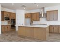 Modern kitchen featuring wood cabinets, a stainless steel range hood, and a large island at 10022 S 37Th Ave, Laveen, AZ 85339