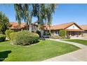 Inviting single-story home with a red tile roof, lush green lawn, mature trees, and neatly trimmed landscaping at 17030 N 57Th St, Scottsdale, AZ 85254