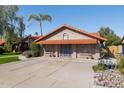 Attached two-car garage with awning in a single-story home with a red tile roof, desert landscaping and mature trees at 17030 N 57Th St, Scottsdale, AZ 85254