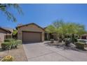 Home with a desert xeriscape front yard featuring various bushes, cactus and trees and a driveway at 17303 N 98Th Pl, Scottsdale, AZ 85255
