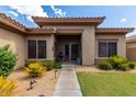 Inviting front entrance featuring a covered porch, desert landscaping, and a freshly manicured green lawn at 2685 N 132Nd Dr, Goodyear, AZ 85395