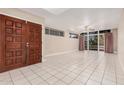 A bright, spacious living room with tile flooring, abundant natural light, and double front doors at 3013 W Port Au Prince Ln, Phoenix, AZ 85053