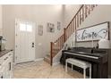Inviting foyer with tile flooring, staircase with wood railings, a piano and a stylish front door at 3308 E Jasper Dr, Gilbert, AZ 85296