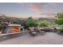 An inviting outdoor space features a stone fireplace, lounge chairs, and desert landscaping at 343 W Twin Peaks Pkwy, San Tan Valley, AZ 85143