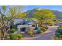Gorgeous home with meticulously maintained landscaping, mature trees, and mountain views in background at 37221 N Holiday Ln, Carefree, AZ 85377