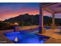 An inviting pool with a fire feature and a beautiful mountain backdrop at twilight at 37221 N Holiday Ln, Carefree, AZ 85377