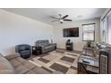 Spacious living room featuring hardwood floors, ceiling fan, large TV, and comfortable couches at 5239 W Leodra Ln, Laveen, AZ 85339