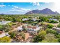Beautiful aerial view of an estate featuring a circular driveway, stunning mountain backdrop and sparkling swimming pool at 6701 E San Miguel Ave, Paradise Valley, AZ 85253
