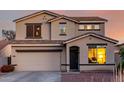 A close up of the home's facade with an attached garage and dark-colored trim at dusk at 1647 W Gold Mine Way, San Tan Valley, AZ 85144