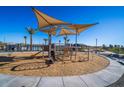 Community playground featuring a slide, climbing equipment, and sunshade structures with wood chip ground cover at 16963 W Poinsettia Dr, Surprise, AZ 85388