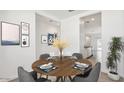 Charming dining room with a round table set for six, modern artwork, and a view into other rooms at 39985 W Agave Rd, Maricopa, AZ 85138