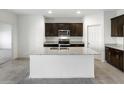 Modern kitchen with a large center island, granite countertops, dark cabinets, and stainless steel appliances at 42895 W Vincent Dr, Maricopa, AZ 85138