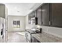 Modern kitchen featuring stainless steel appliances, dark cabinets and granite countertops at 42925 W Peters Dr, Maricopa, AZ 85138