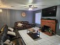 Cozy living room featuring a brick fireplace, comfortable leather seating, and a ceiling fan for added comfort at 4507 E Saint Catherine Ave, Phoenix, AZ 85042
